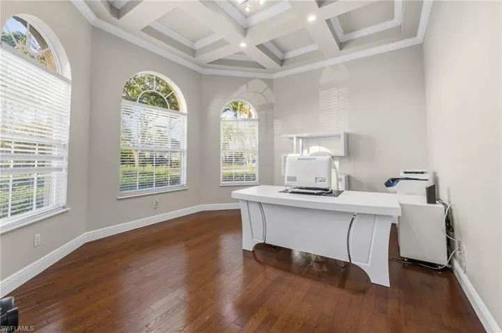 Office space with coffered ceiling, dark wood-style flooring, beam ceiling, ornamental molding, and recessed lighting