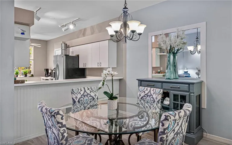 Dining area with a notable chandelier, light wood-type flooring, and track lighting