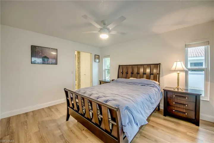 Bedroom with ceiling fan, multiple windows, light wood-type flooring, and baseboards