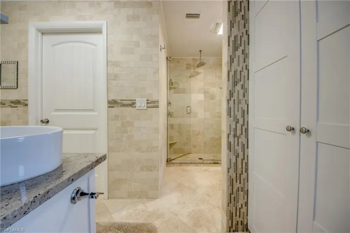 Bathroom featuring tile walls, visible vents, a stall shower, vanity, and tile patterned floors