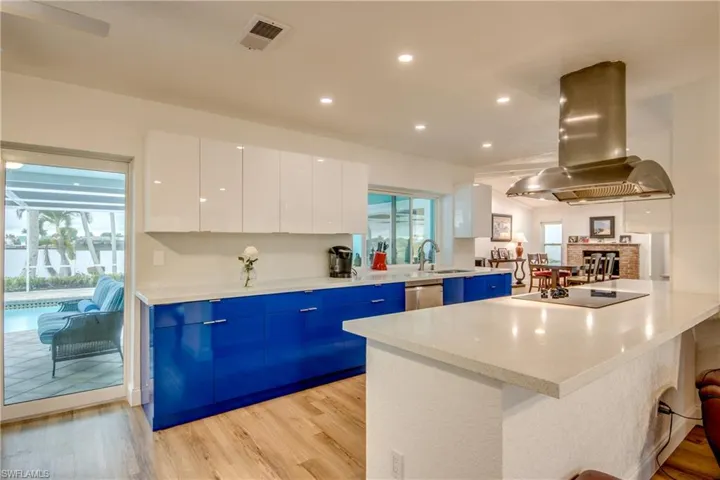 Kitchen featuring light countertops, white cabinetry, island exhaust hood, and black electric stovetop