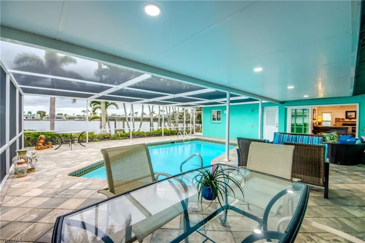 Pool featuring a water view, screened enclosure, outdoor lounge area, and a patio