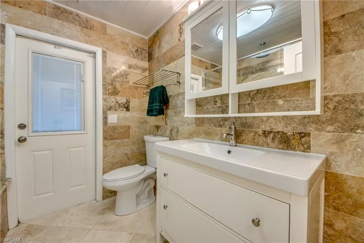 Bathroom featuring visible vents, toilet, tile walls, and vanity