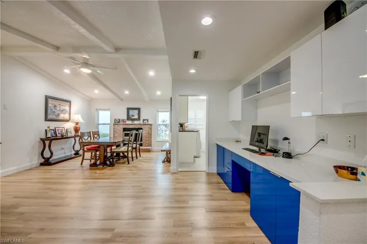 Kitchen with lofted ceiling with beams, visible vents, light wood-style floors, white cabinets, and modern cabinets