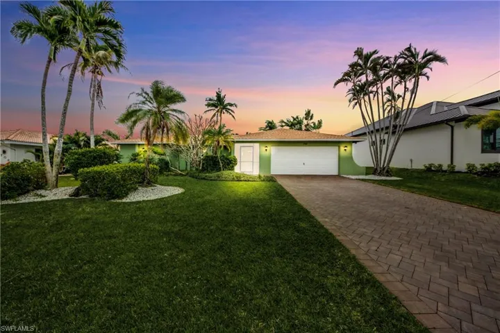 View of front of property with decorative driveway, a lawn, an attached garage, and stucco siding