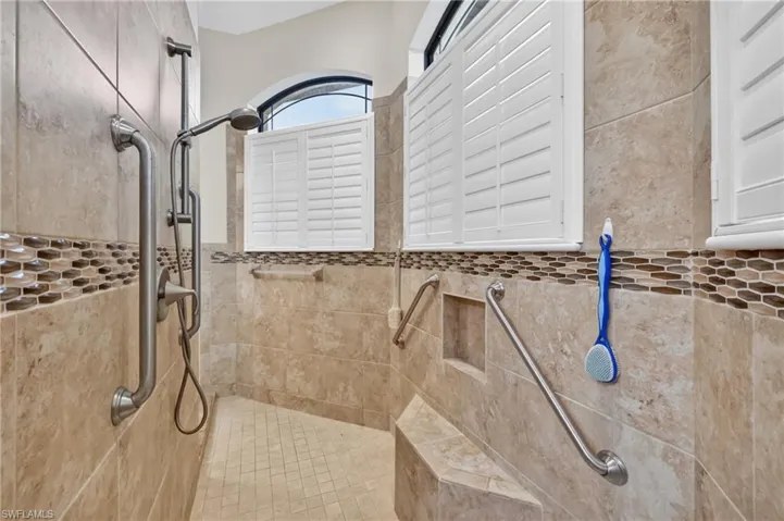 Walk-in shower with full tile surround, integrated bench seating, and multiple grab bars