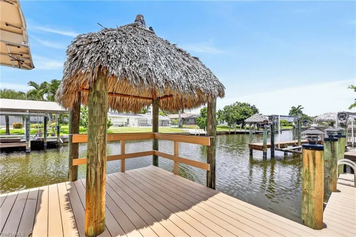 Waterfront property featuring Tiki with a private dock with a boat lift and canopy