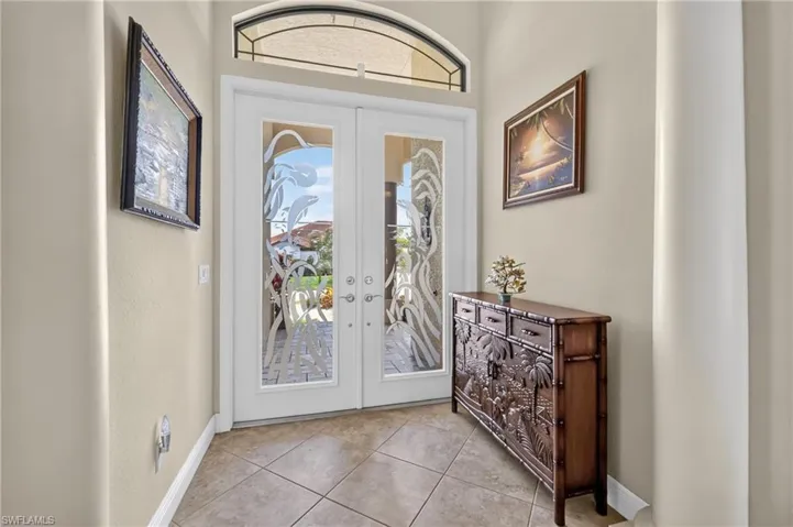 Entryway featuring double glass-paneled doors with decorative frosted accents, a transom window above, and large format tile flooring