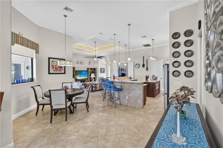 Open-concept living area featuring large format floor tiles, a coffered ceiling with accent lighting, and recessed lighting
