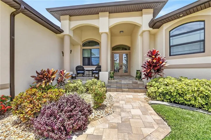 Elegant stucco exterior featuring arched entryways, decorative columns, and a double-door entry with etched glass