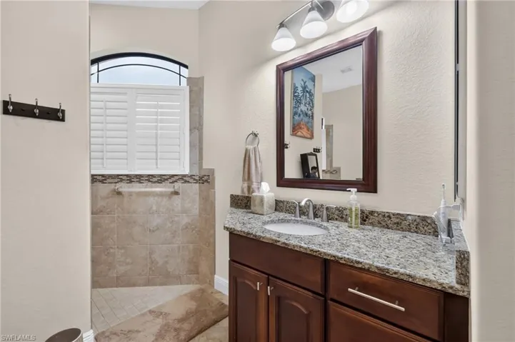 Bathroom featuring a vanity with granite countertop, undermount sink, and dark wood cabinetry