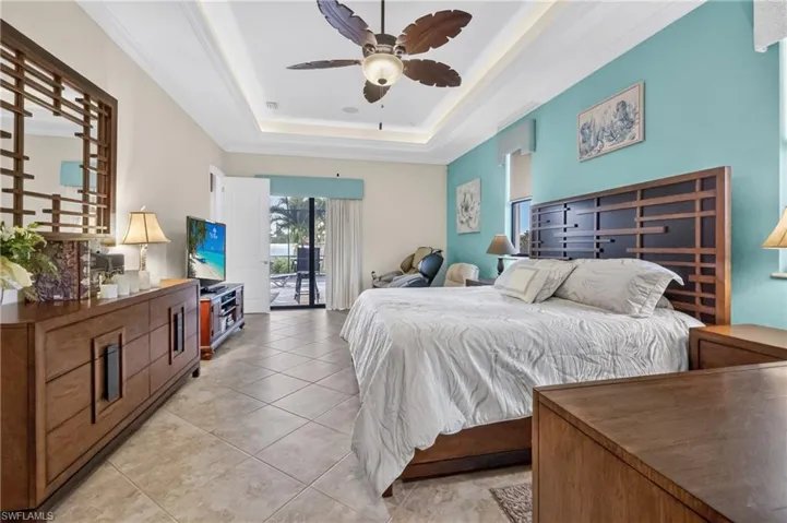 Spacious room featuring tile flooring, a tray ceiling with a ceiling fan, and direct access to an outdoor patio through sliding glass doors