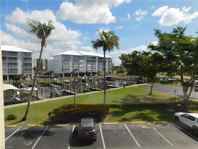 View of parking / parking lot featuring a water view and a yard