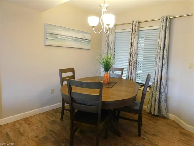 Dining space with dark hardwood / wood-style floors and a notable chandelier