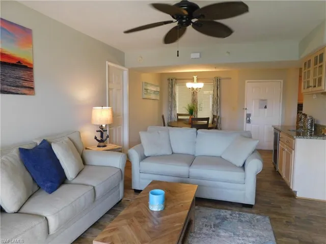 Living room featuring ceiling fan with notable chandelier, dark hardwood / wood-style flooring, and wine cooler