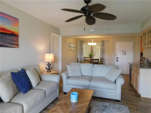 Living room with wine cooler, dark hardwood / wood-style flooring, and ceiling fan with notable chandelier