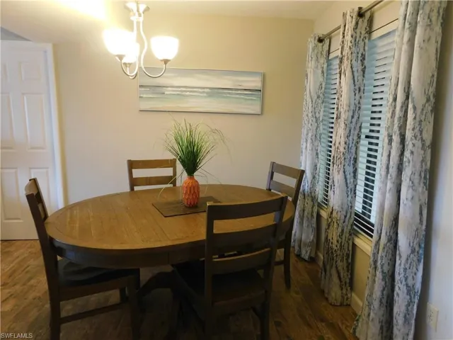 Dining space with dark hardwood / wood-style flooring and an inviting chandelier