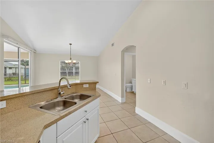 Kitchen with white cabinetry, light countertops, light tile patterned floors, hanging light fixtures, and a chandelier