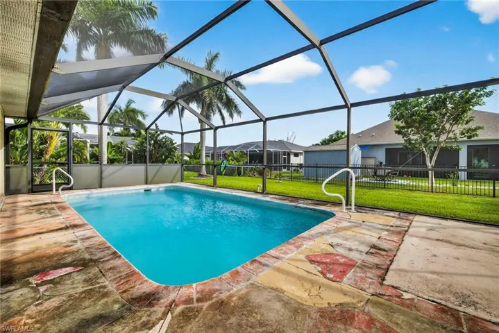 View of pool featuring glass enclosure, a sunroom, a patio area, and a residential view
