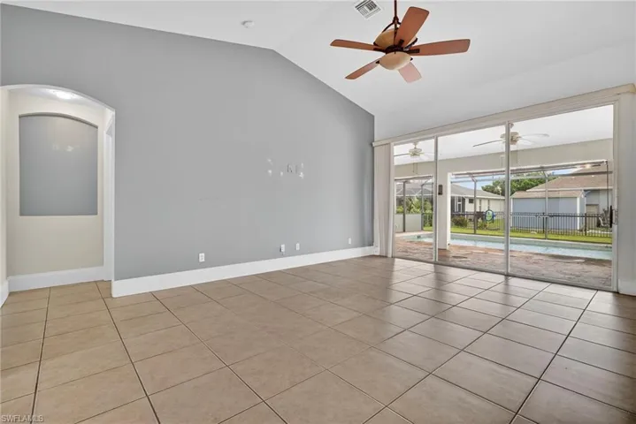 Tiled empty room with lofted ceiling and a sunroom