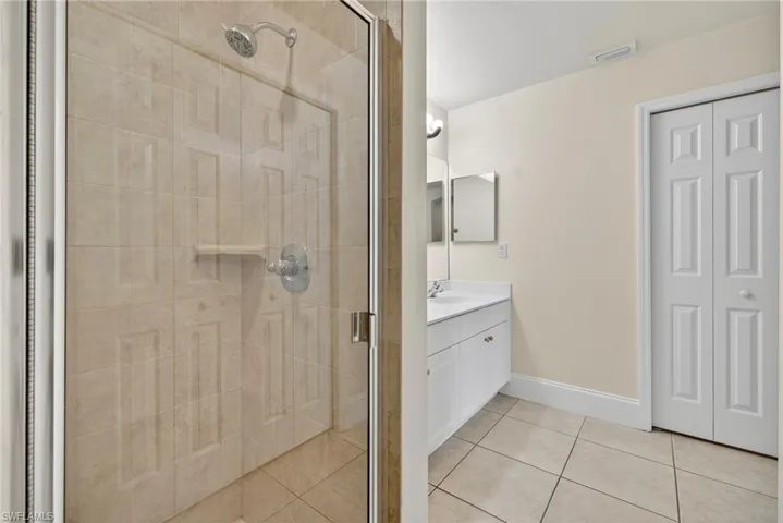 Full bath with vanity, a shower stall, and light tile patterned floors