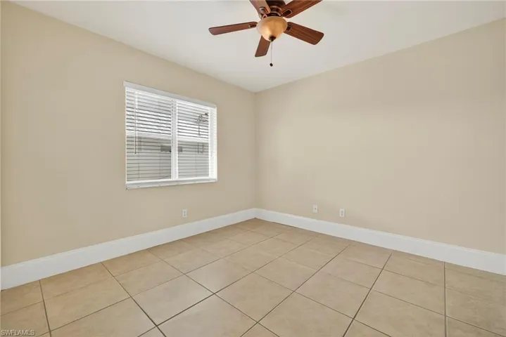 Empty room with light tile patterned flooring and ceiling fan