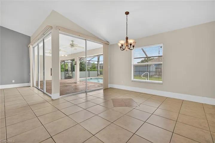 Unfurnished dining area with vaulted ceiling, healthy amount of natural light, light tile patterned flooring, a sunroom, and a chandelier