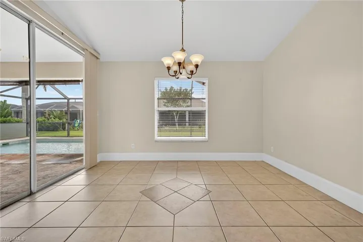 Unfurnished dining area with light tile patterned floors, a sunroom, a chandelier, and lofted ceiling