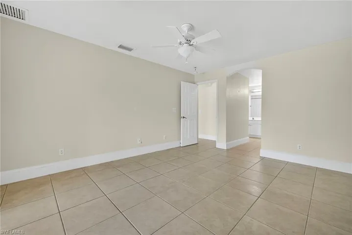 Unfurnished room featuring light tile patterned floors, arched walkways, and ceiling fan