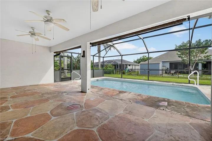 Swimming pool featuring a patio area, ceiling fan, glass enclosure, and a sunroom