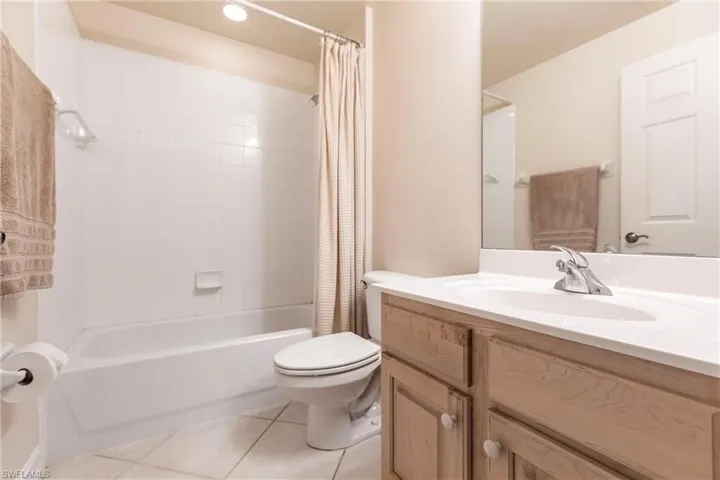 Full bathroom with shower / bath combo with shower curtain, tile patterned floors, vanity, and toilet