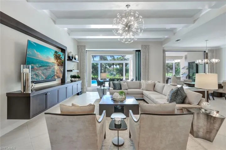 Tiled living room featuring a notable chandelier, beamed ceiling, and plenty of natural light