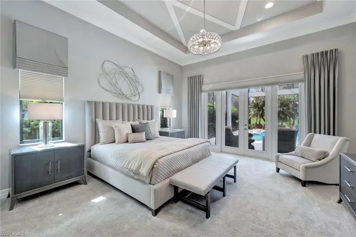 Carpeted bedroom featuring french doors, access to outside, multiple windows, and an inviting chandelier