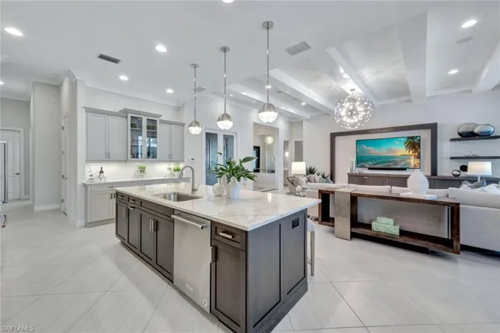 Kitchen with a kitchen island with sink, sink, pendant lighting, stainless steel dishwasher, and tasteful backsplash