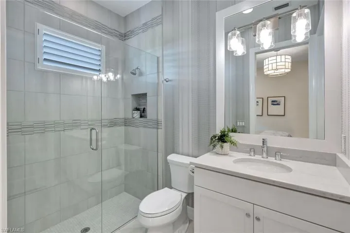 Bathroom featuring vanity, toilet, and a shower with door