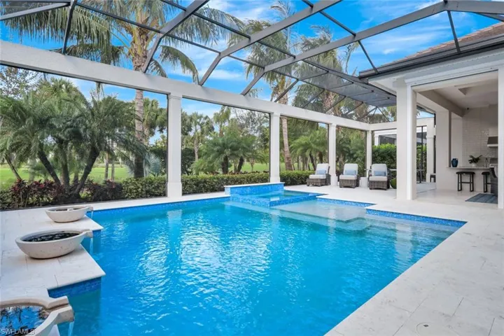 View of swimming pool featuring a patio, a hot tub, an outdoor bar, and glass enclosure