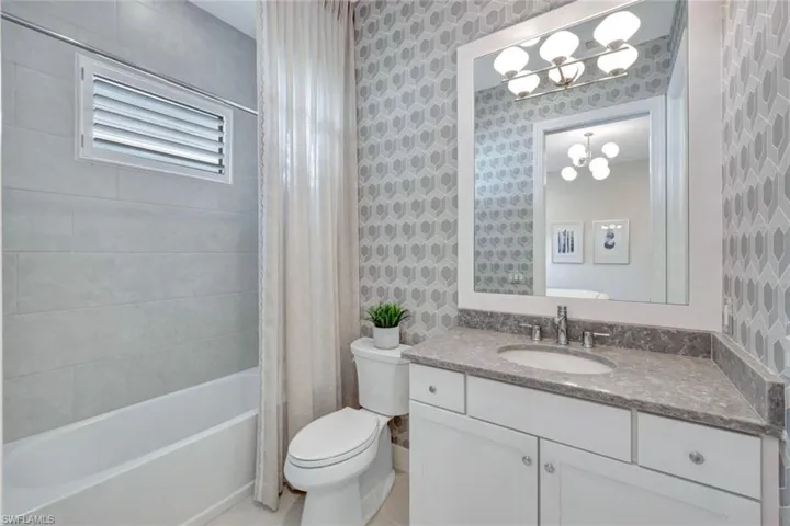 Full bathroom with vanity, shower / bath combo, and toilet