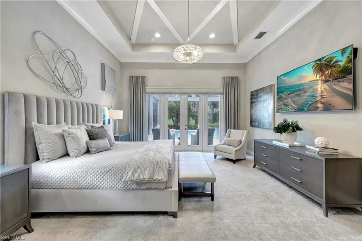 Bedroom featuring french doors, access to exterior, a tray ceiling, light colored carpet, and a towering ceiling