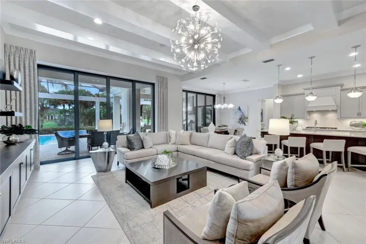 Tiled living room featuring ornamental molding, a chandelier, and beamed ceiling