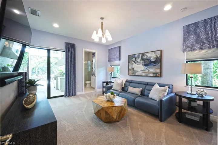 Carpeted living room featuring a chandelier and plenty of natural light