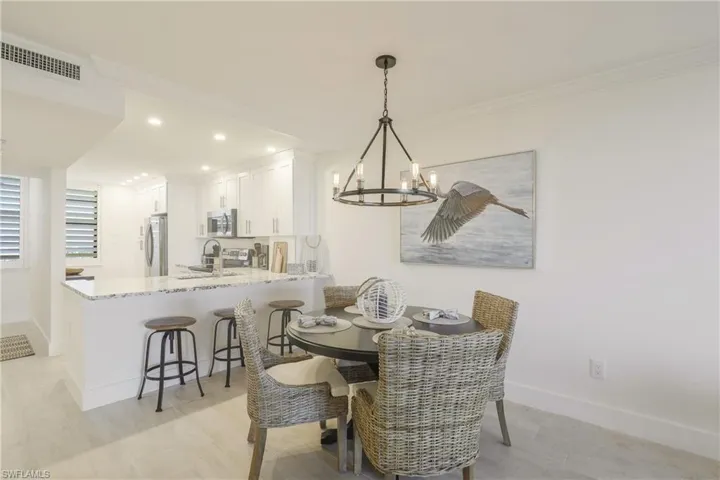 Dining room with suspended lighting, light wood-type flooring, and crown molding