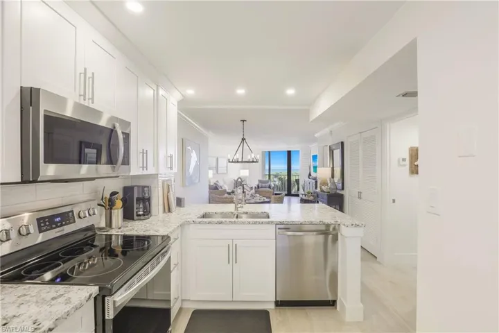 Kitchen with stainless steel appliances, a peninsula, open floor plan, white cabinets, and crown molding