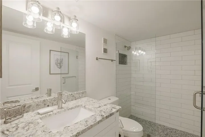Full bath featuring vanity, a stall shower, and suspended lighting