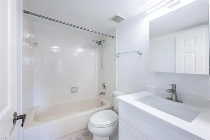 Bathroom featuring toilet, vanity, tub / shower combination, and visible vents