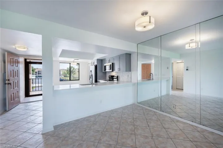Kitchen with light tile patterned flooring, light countertops, a peninsula, appliances with stainless steel finishes, and a sink
