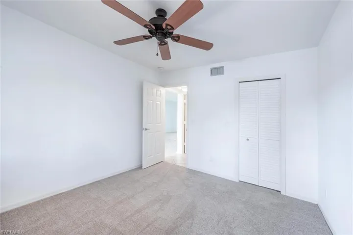 Unfurnished bedroom featuring a closet, carpet flooring, a ceiling fan, baseboards, and visible vents