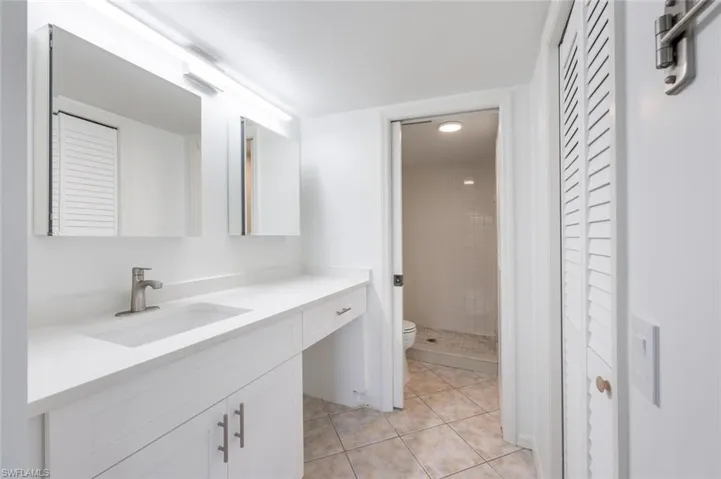 Full bathroom featuring toilet, a stall shower, tile patterned flooring, and vanity