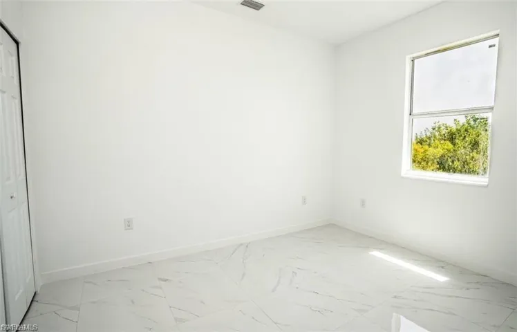 Unfurnished room featuring baseboards and light marble finish floors