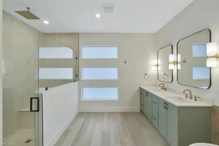 Full bathroom with a marble finish shower, light wood-type flooring, double vanity, and recessed lighting