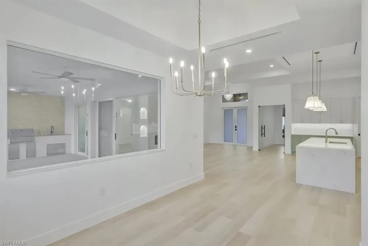 Unfurnished dining area featuring light wood-type flooring, hanging lights, a tray ceiling, and a ceiling fan